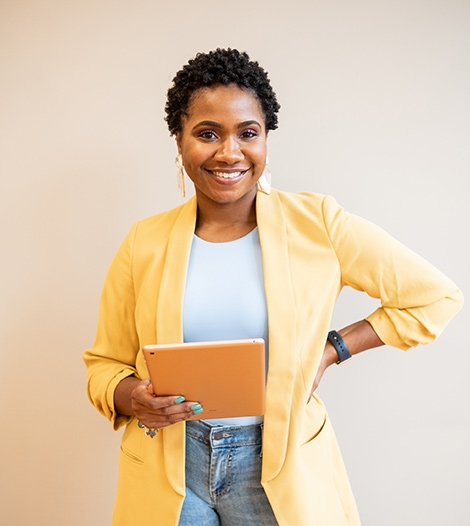 business-woman-smiling-with-yellow-blazer-holding-a-tablet